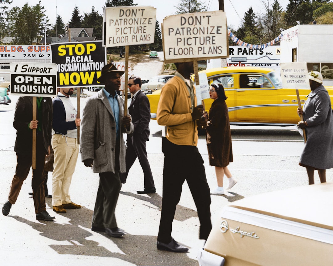 Protestors hold signs reading Stop Racial Discrimination Now! during a demonstration at Picture Floor Plans, Inc.