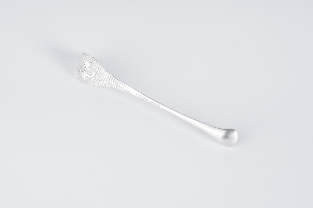 a spoon with a white handle on a white surface