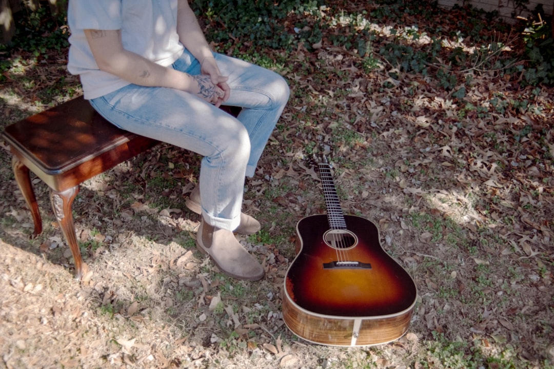 Person sitting on bench with guitar on ground