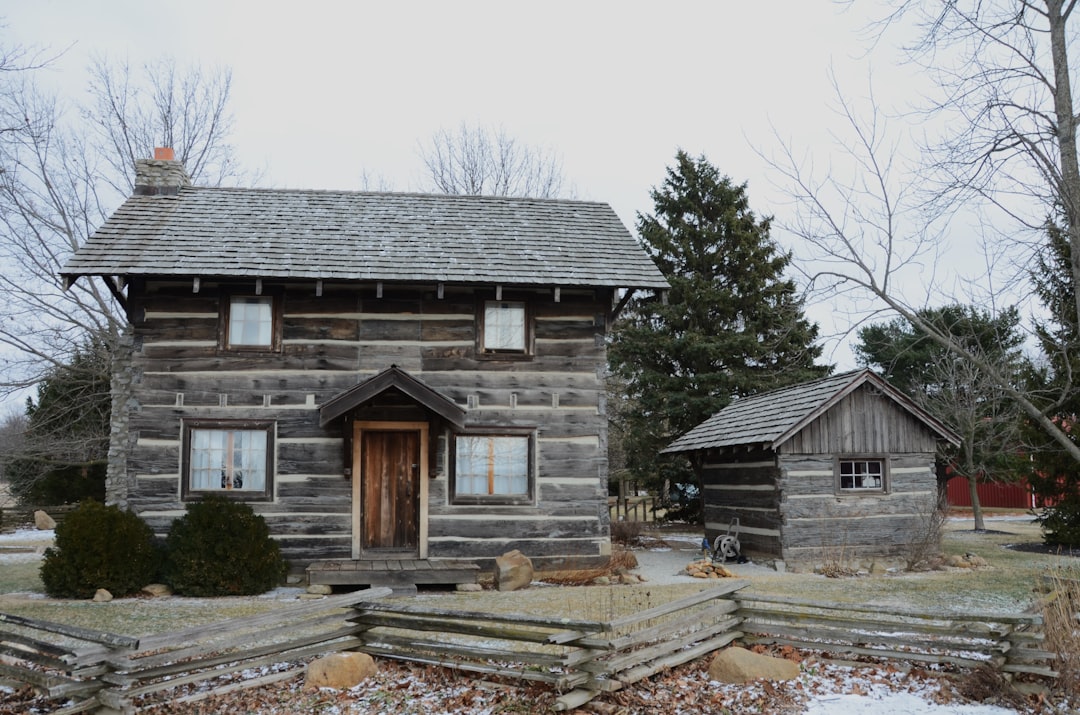 Rustic log cabin with a small shed and wooden fence.