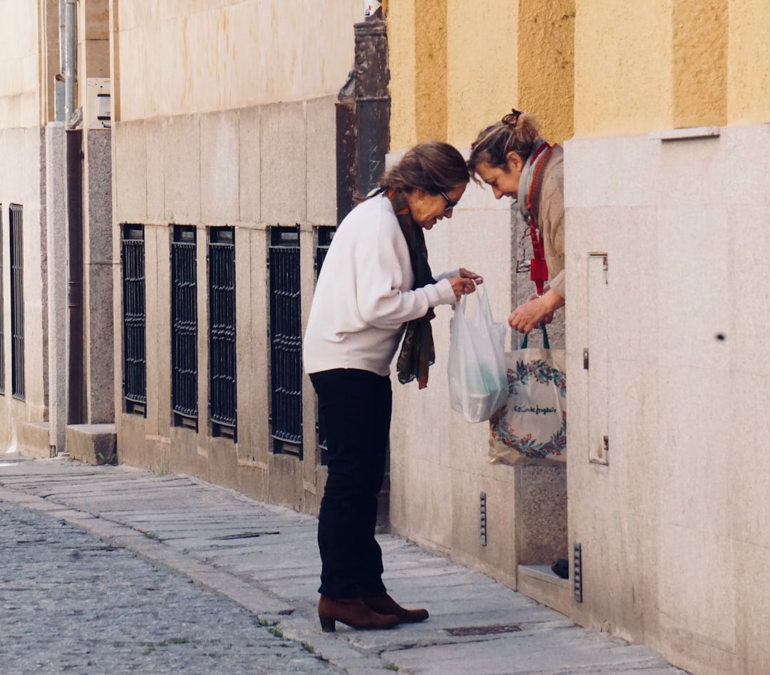 Two Spanish women peering into a bag on the street in a doorway heads touching