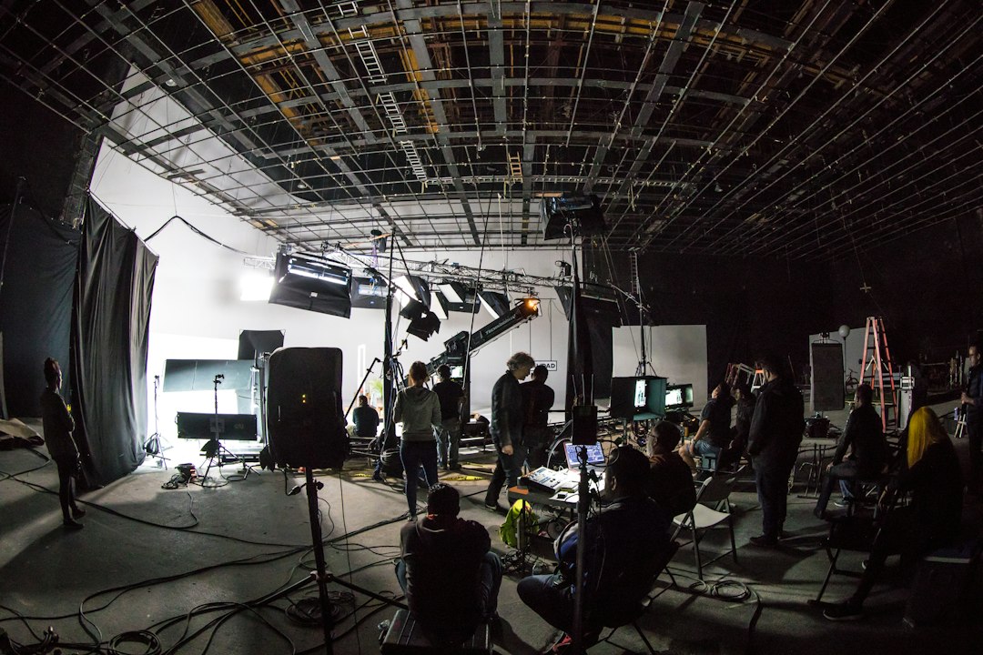 A film crew working on a large soundstage with lighting equipment and cameras