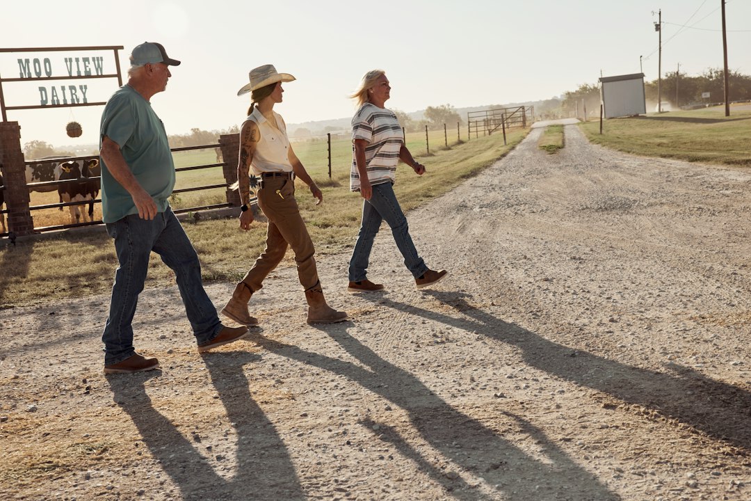 Three farmers walking across a farmyard
